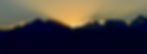Sunrise over mountains, with golden light radiating behind peaks. Silhouetted landscape, clear sky, creating a serene and majestic scene.