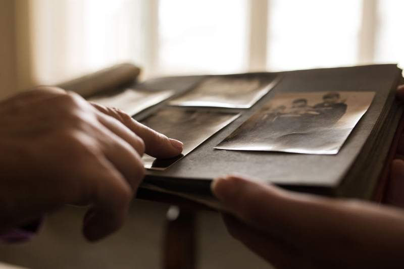 Close up human hand pointing to photo in photo album_800x533