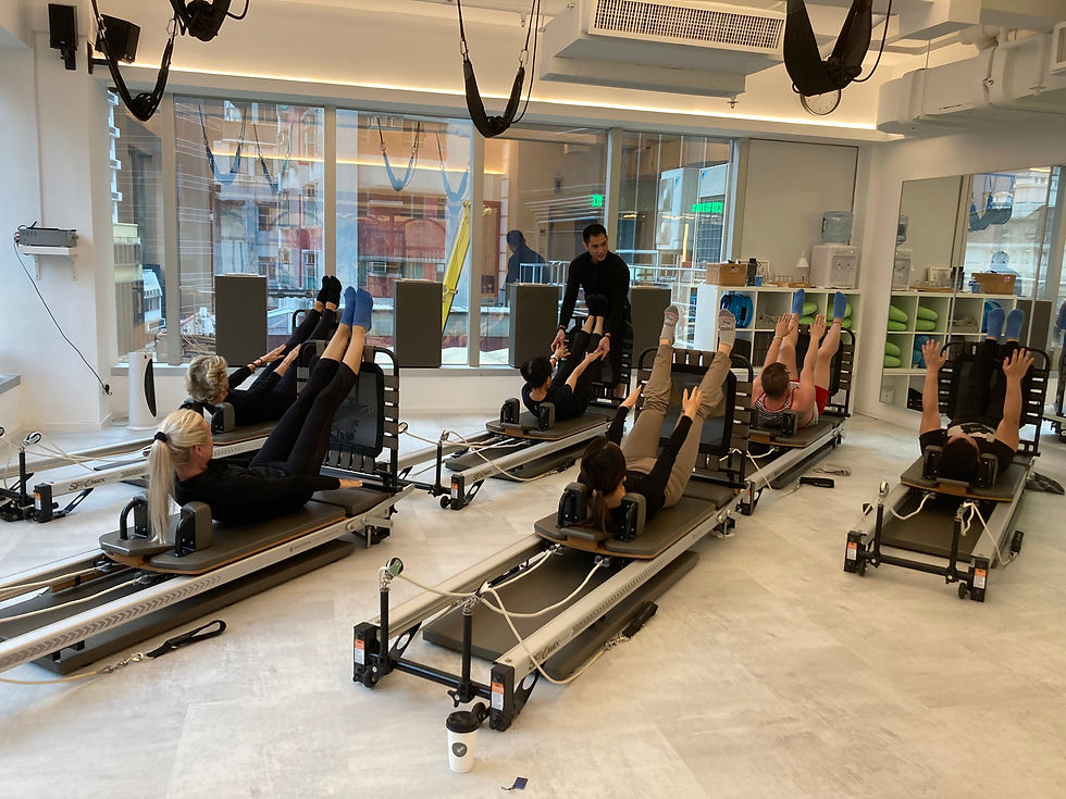 A diverse group of individuals practicing Pilates together in a well-equipped gym environment.