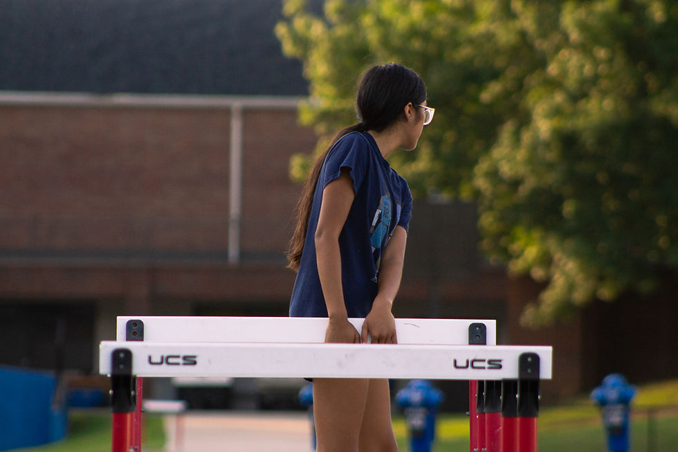 Memphis Mustangs athlete standing behind track hurdles