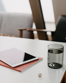Tisch mit einem Tablet, Notixheften und einem Glas Wasser