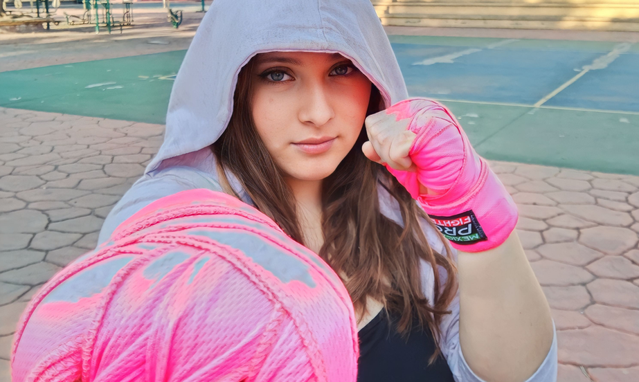 lumna con guantes en posición de guardia durante sesión de artes marciales.