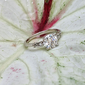 Antique style engagement ring with a round diamond sitting on a leaf
