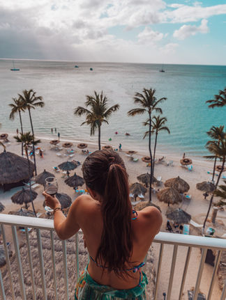 A woman looking down from the balcony at the beach in Aruba