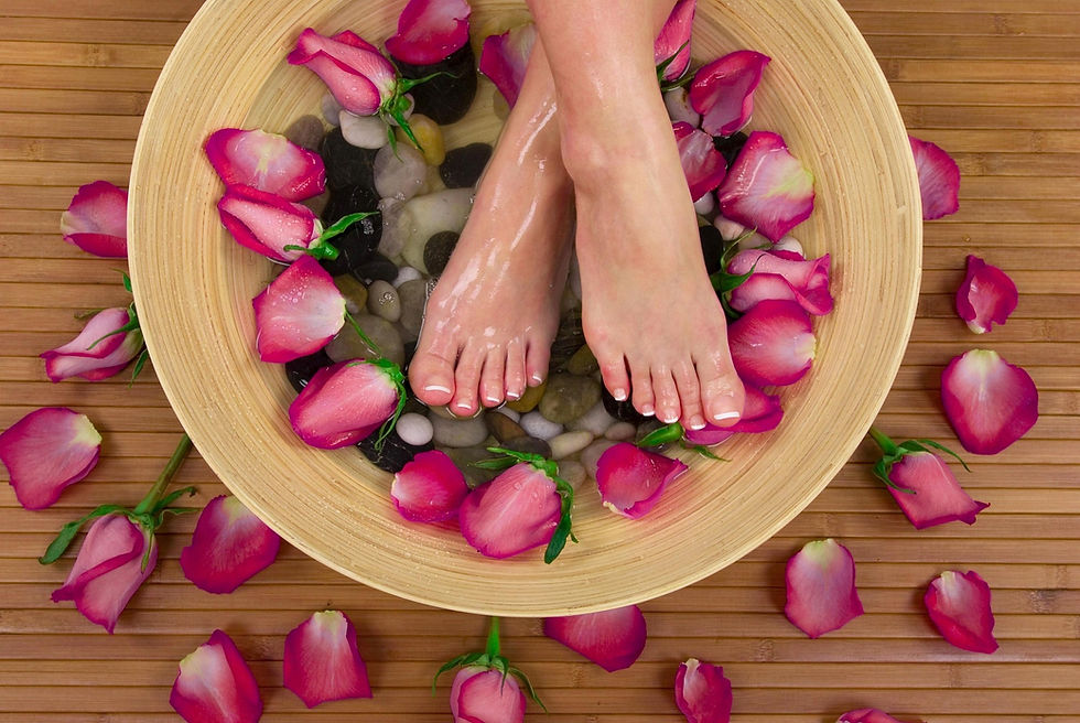 Feet in a bowl of water with pink petals.