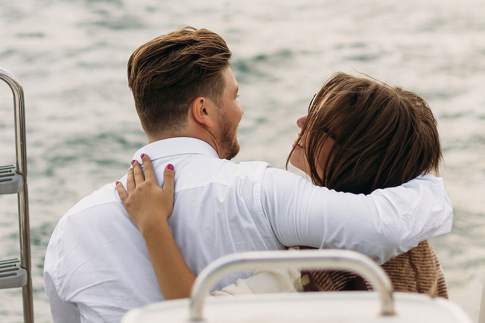Man and women on a boat in the sea, cuddling each other.