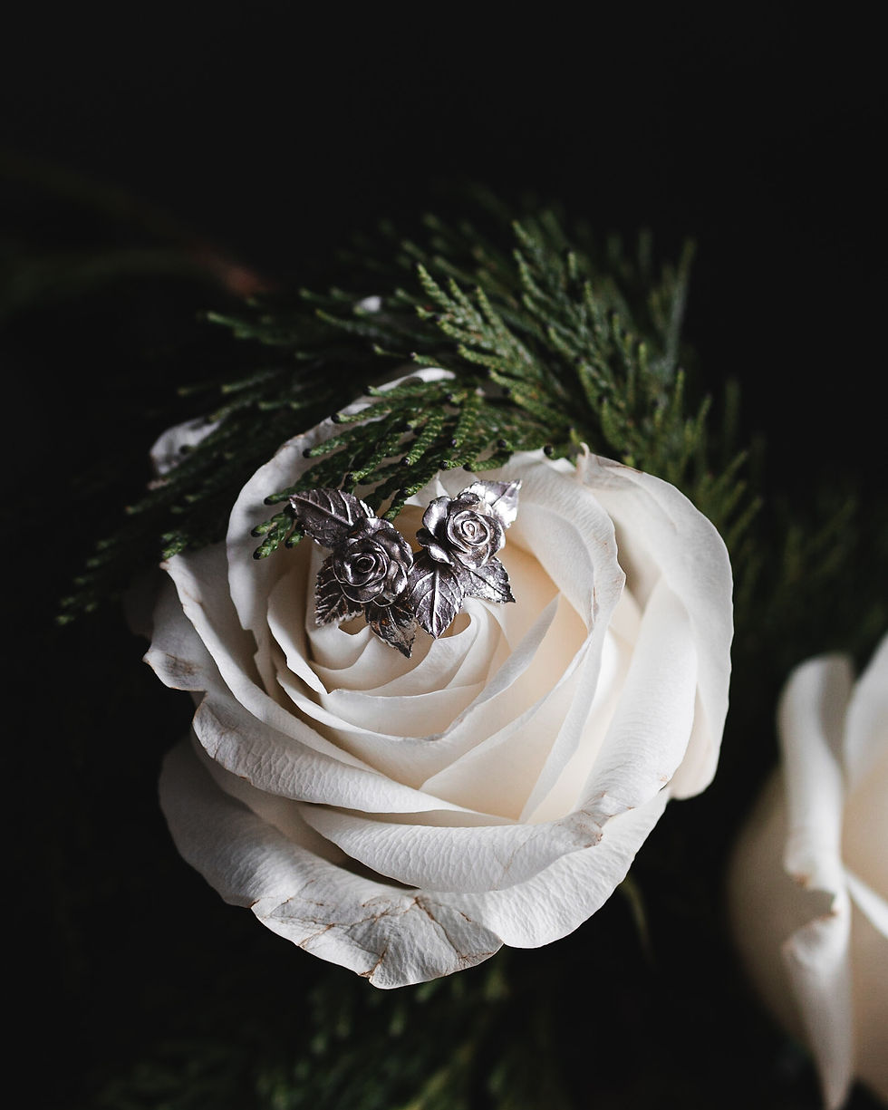 Thumbnail: Silver rose and leaf large stud earrings placed on a white rose
