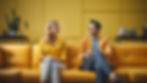 Cinematic shot of a man and woman in business casual attire, sitting on an orange couch in a bright yellow office. They're engaged in animated conversation, smiling at each other in a modern, minimalist interior with vibrant colors and natural daylight