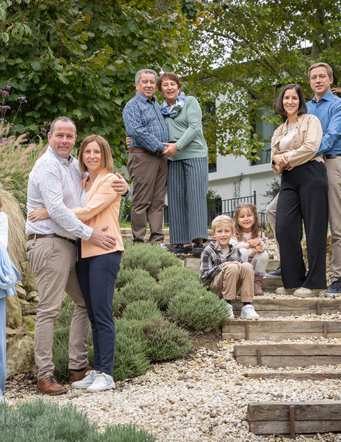 Großeltern, Eltern und Kinder genießen einen sonnigen Tag draußen im Grünen.