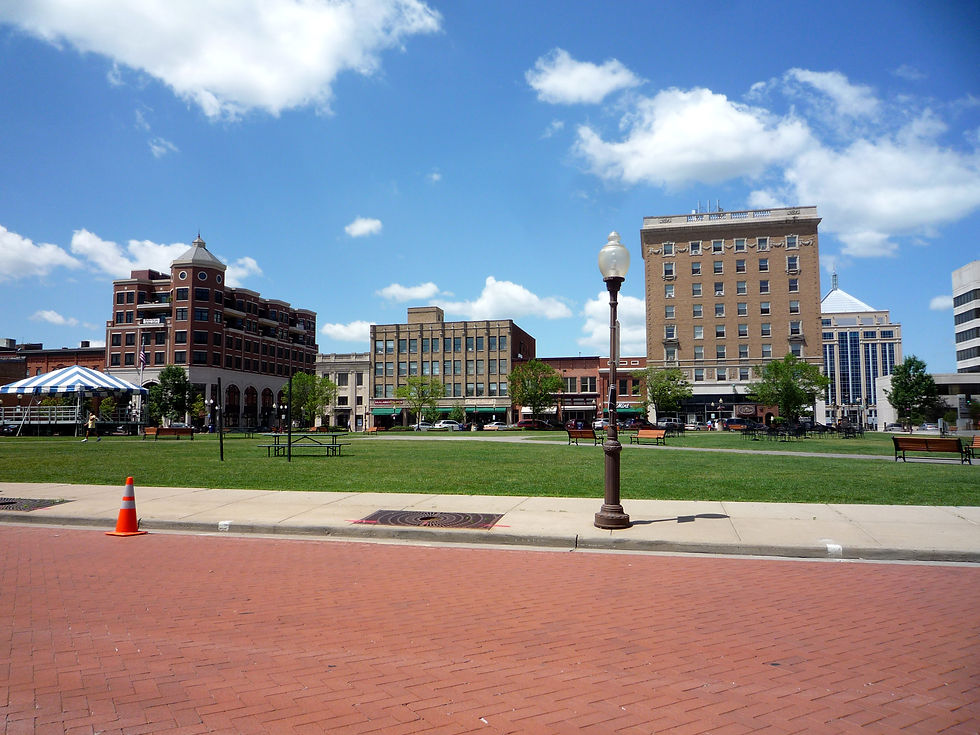 The 400 Block plaza lawn with historic downtown Wausau buildings under a blue sky