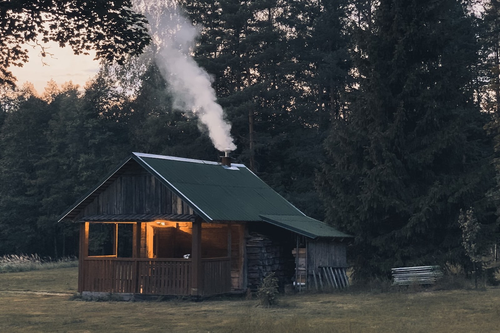 cabin with smoke coming out of chimney near trees, empty of people