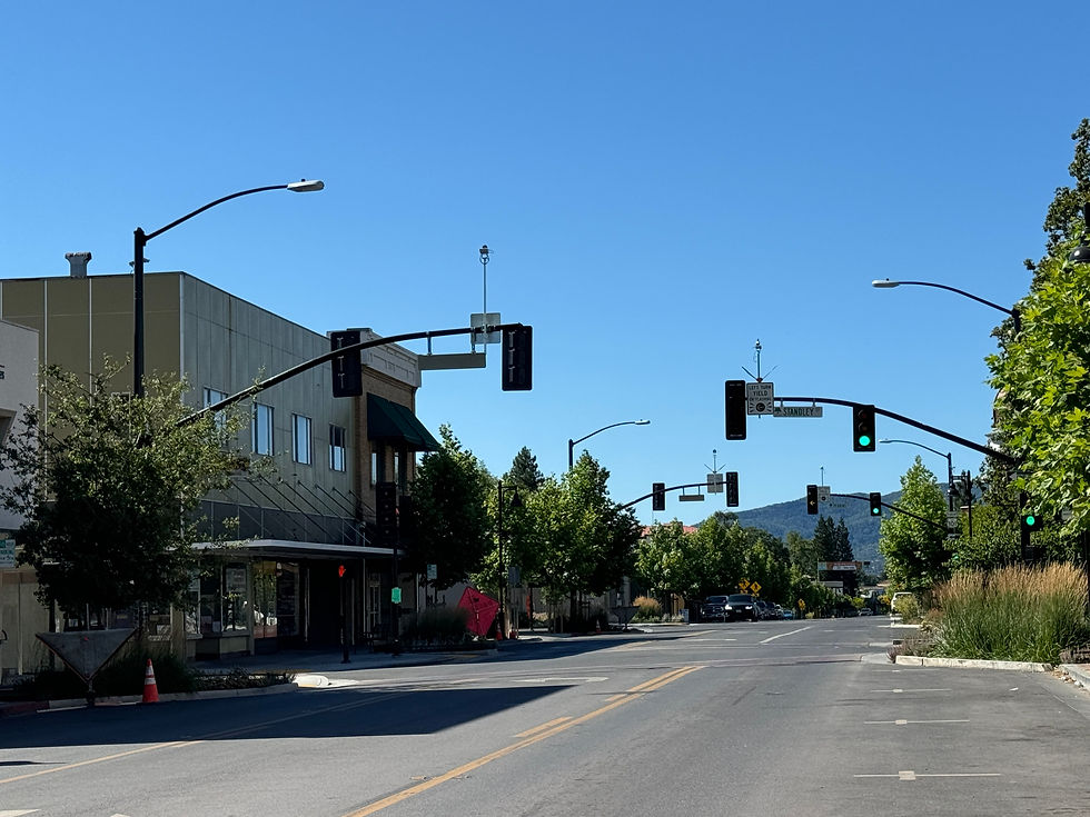 Downtown Ukiah street with traffic signals, trees and hills on a sunny California morning