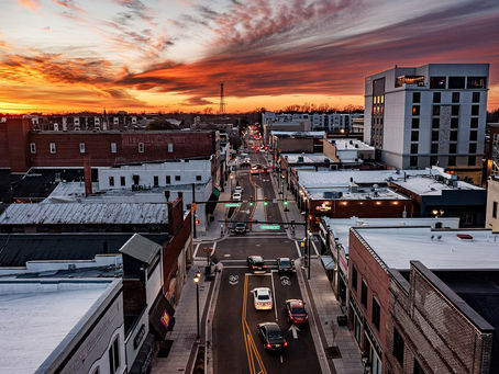 Downtown Greenville NC street at sunset looking along the corridor — rooftops and roadway, no people as subject