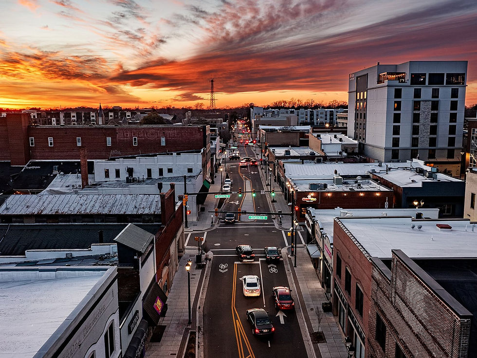 Downtown Greenville NC street at sunset looking along the corridor — rooftops and roadway, no people as subject