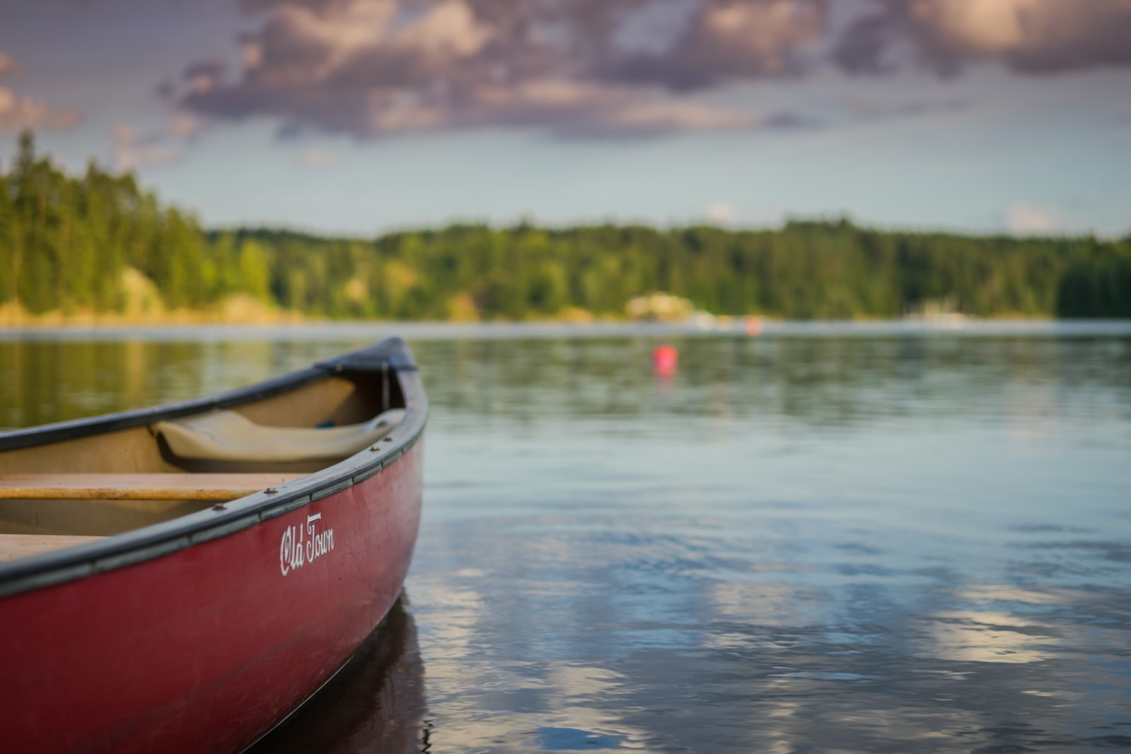 red canoe boat on body of water, empty of people