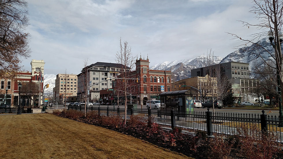 Historic brick buildings along a downtown Provo street with Wasatch peaks behind