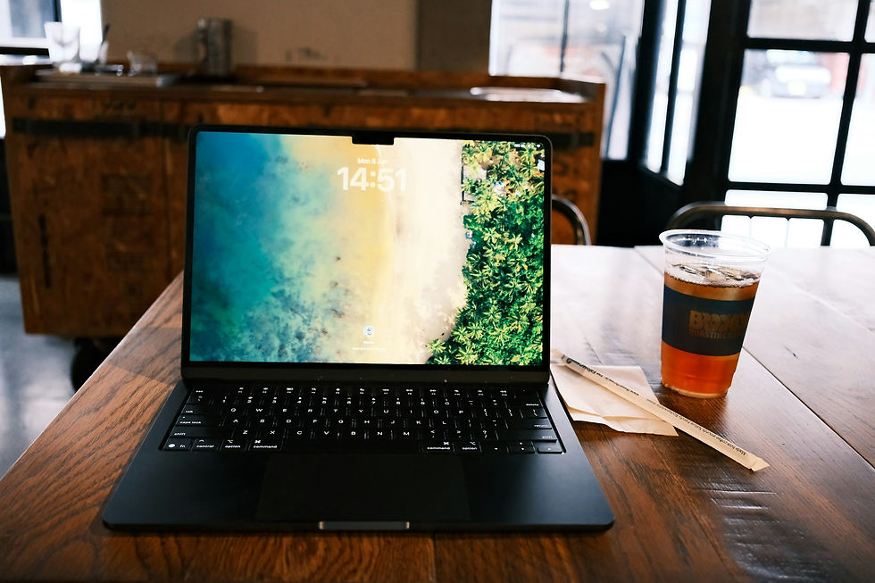 Black laptop and iced drink on a wooden table
