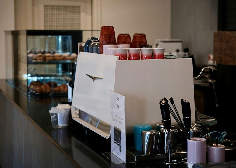 Espresso machine with cups and pastries in background