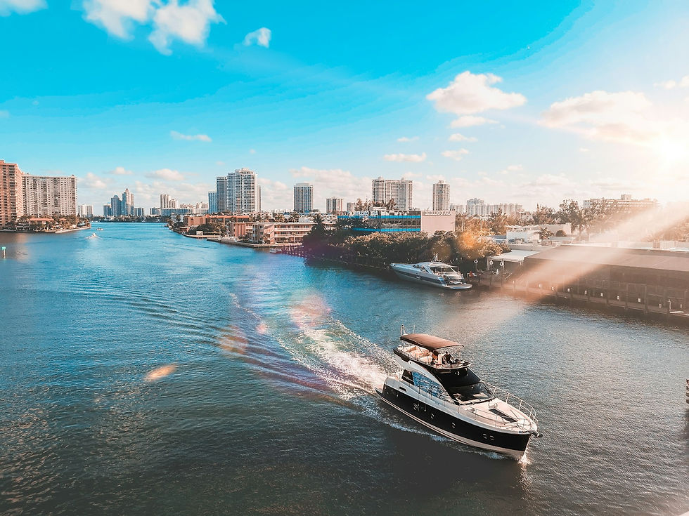 A white and black boat running across the blue water of Biscayne Bay with the Miami Beach skyline behind it on a clear day