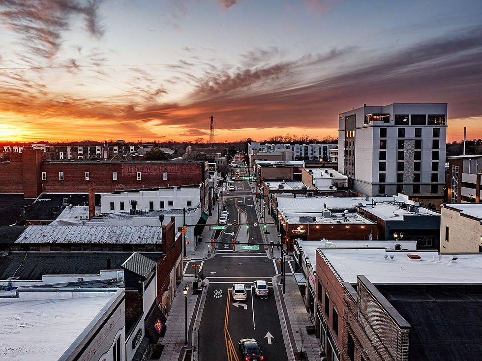 Downtown Greenville NC street corridor at sunset — buildings and roadway, no people as subject