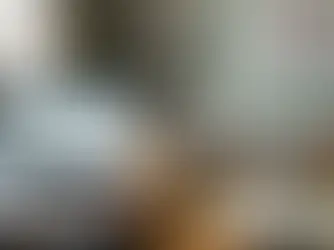 Tablet mit steigenden Marktdaten-Graphen im Fokus einer minimalistischen Galerie; im unscharfen Hintergrund betrachtet ein Investor eine zeitgenössische Chrom-Skulptur. Symbolbild für datengestütztes Kunstinvestment und Blue-Chip-Marktanalyse.