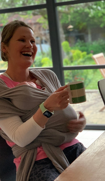Young woman laughing and sitting at a table, drinking tea.
