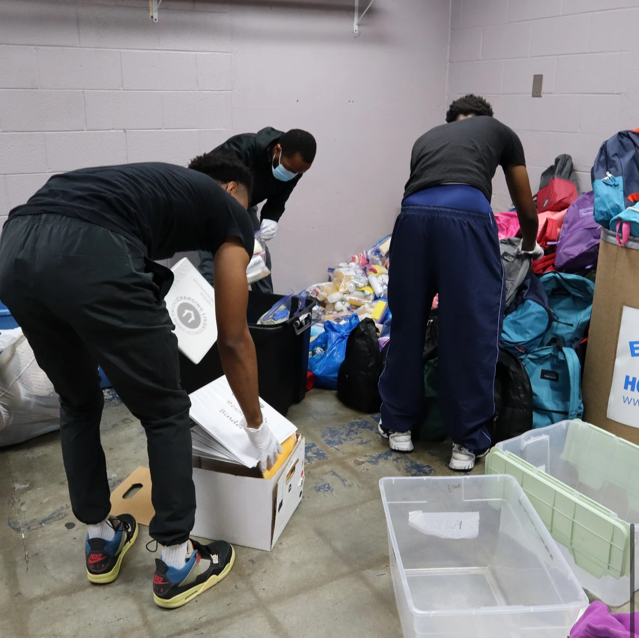 Volunteers sorting hygiene supplies and backpacks