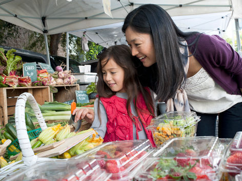 A woman and her daughter shop at a farmers market.
