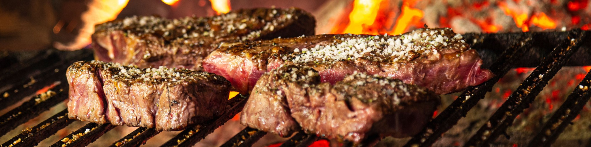 Steaks cooking over an open wood fire