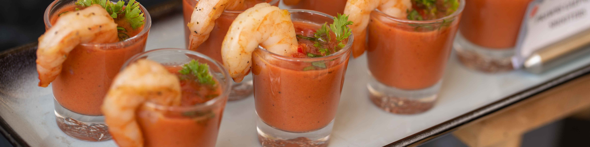 Shrimp garnished gazpacho shots served on a tray