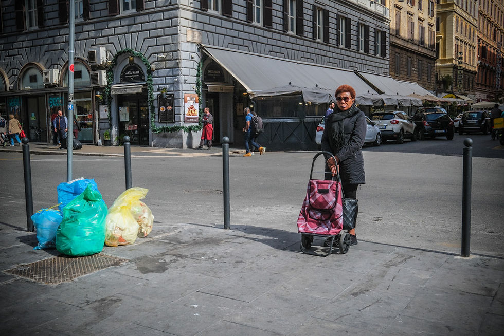 Donna con carrello della spesa accanto a sacchi di rifiuti in strada, contrasti sociali nell’Esquilino convivenze parallele – Foto © Giorgio Cosulich