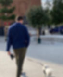 a man and a dog walking outside arriving at a meeting