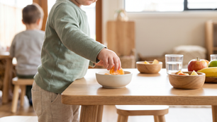 Toddler reaching across a wooden table to pick up a mandarin segment at The Green Elephant, illustrating everyday foods that support winter immunity