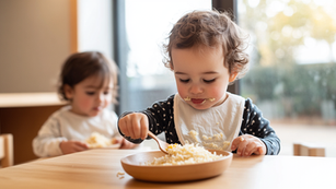 Toddler self-serving food from a bowl onto their plate at a childcare mealtime setting