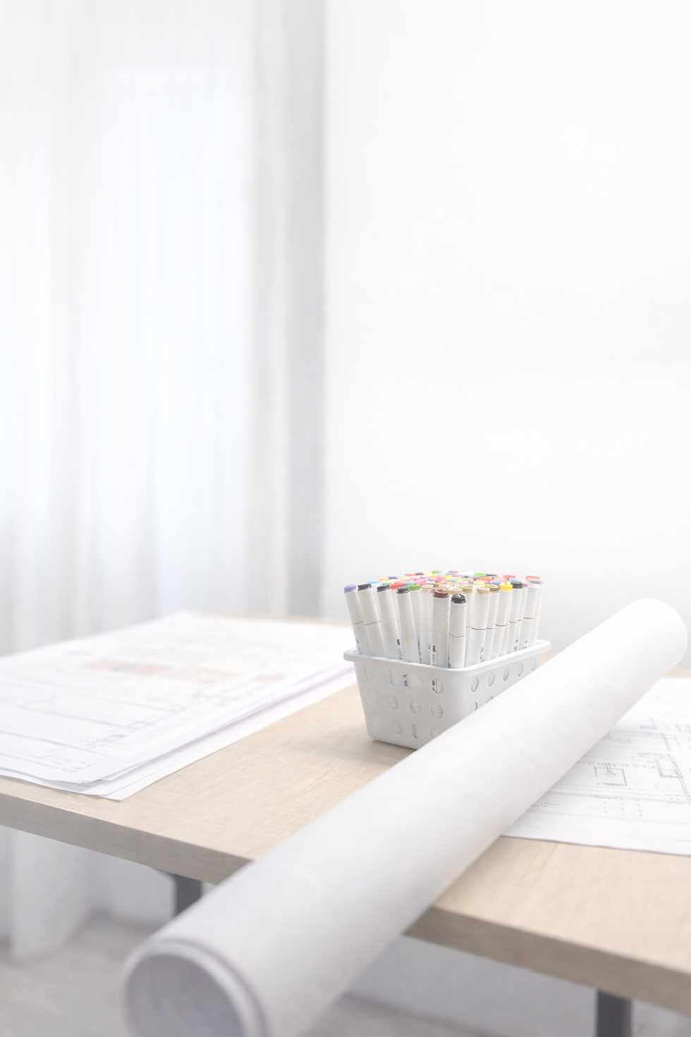 Mesa de trabajo con planos de diseño, marcadores y documentación de proyecto de interiorismo y paisajismo