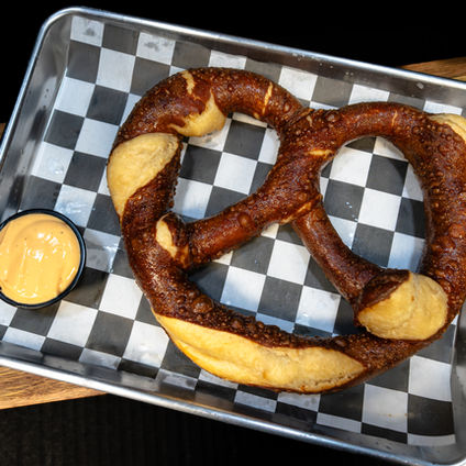 Large soft pretzel with cheese dip on a tray