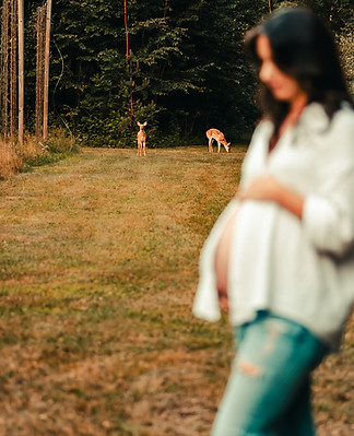 Boudoir maternity photo of expecting mother with fawn in background