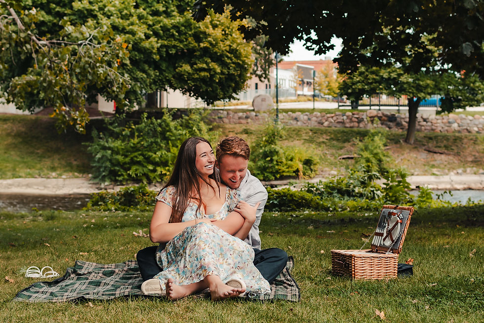 A newly engaged couple sit together, embraced and laughing, next to an open picnic basket. The image links to a webpage about Date Night Sessions.
