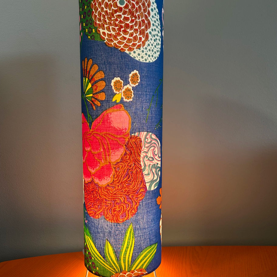 Sylinderformet blå bordlampe med fargerikt blomstermønster
