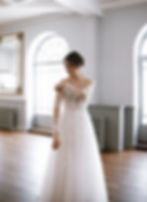 Beautiful bride adjusting her sleeve of her vine covered white dress whilst standing in the main lounge at the Dome