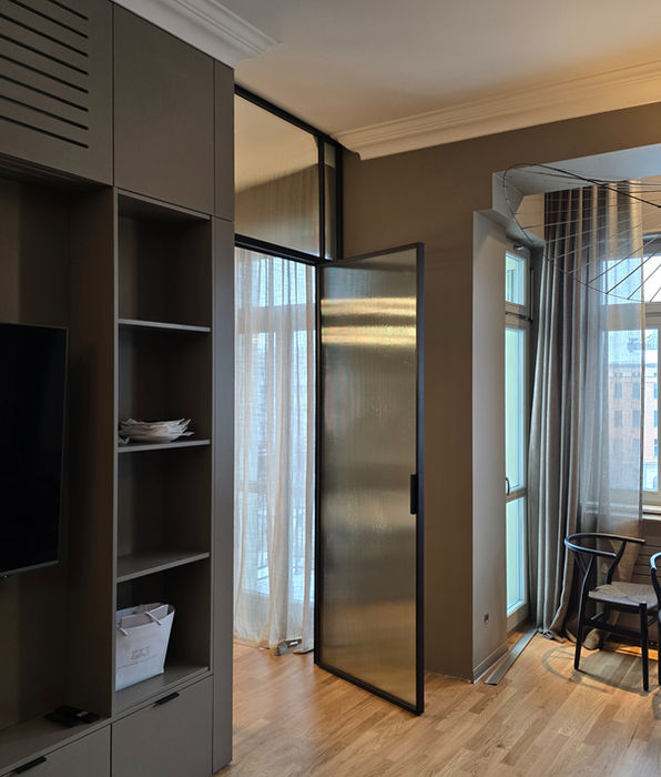 Stahl-Lofttür mit milchigem Strukturglas und Oberlicht im Wohnraum.