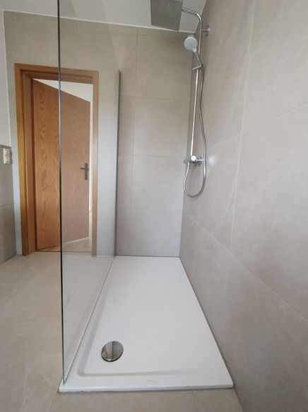 Einstieg in die Dusche mit seitlich montierter Duschsäule und Glasabtrennung