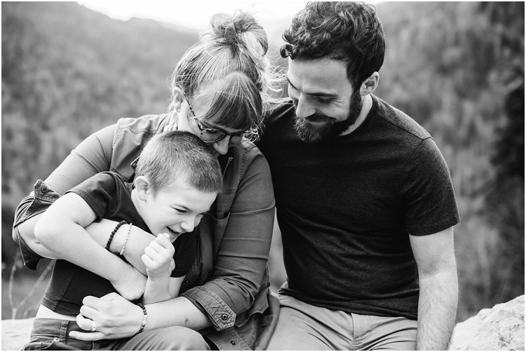 family-sitting-on-rock-ledge-snuggled-close-at-family-session-in-the-great-smoky-mountains-by-green-bay-wedding-photographer-kyra-rane-photography