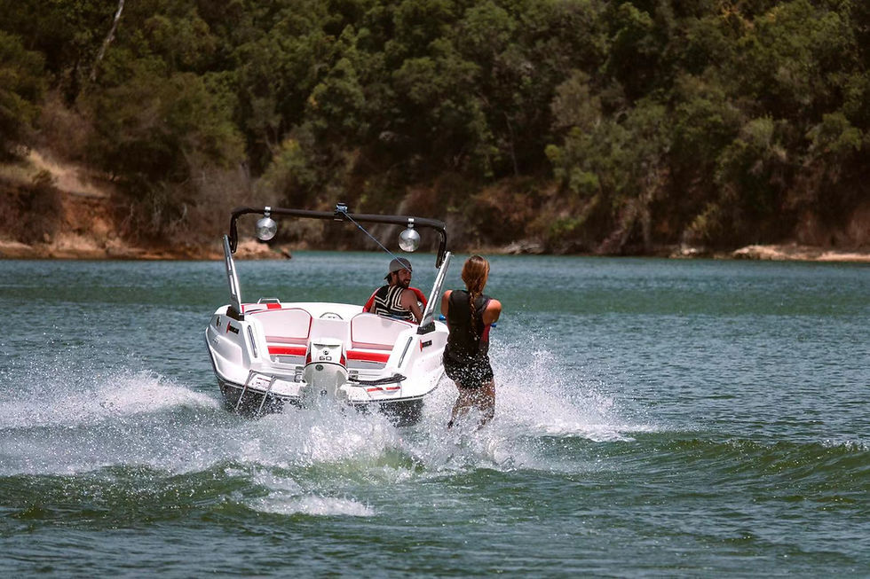 Person wakeboarding behind a red-and-white speed boat on a lake.