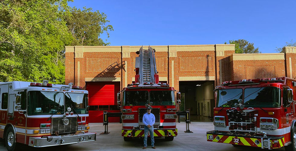Fire board member standing in front of three fire trucks