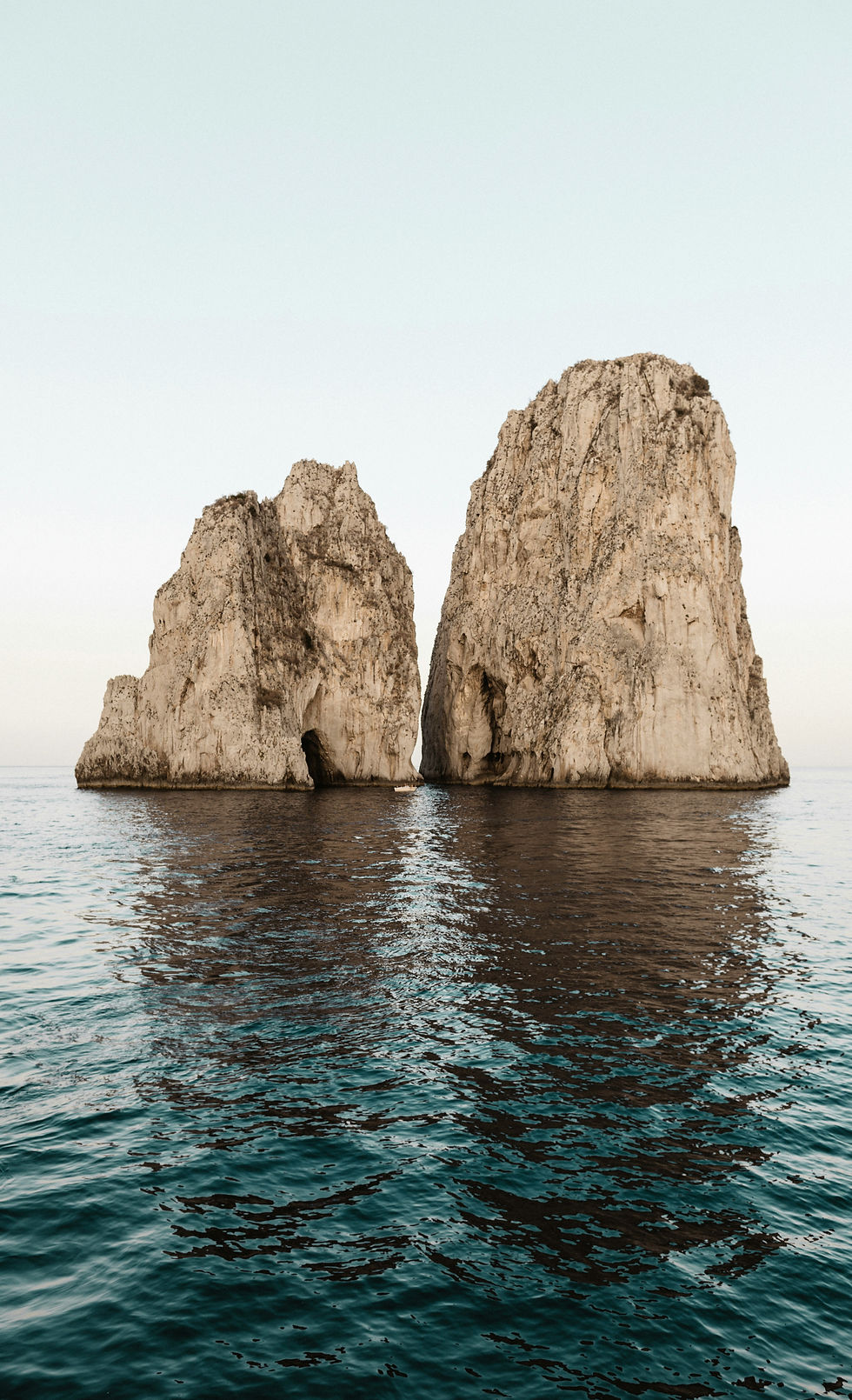 2 different shaped large rocks coming out of the sea