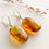 Thumbnail: Light cognac color oval shape amber earrings with insects