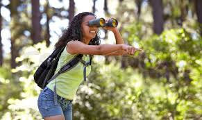 Woman looking through binoculars and pointing