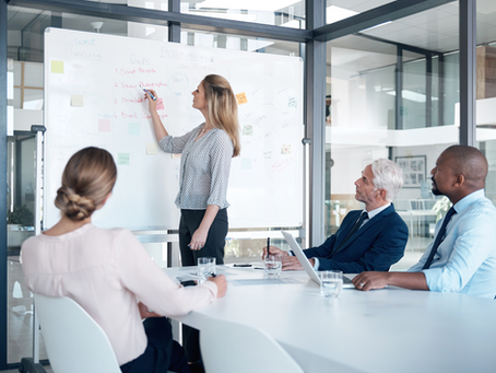 People in office looking at woman writing on white board