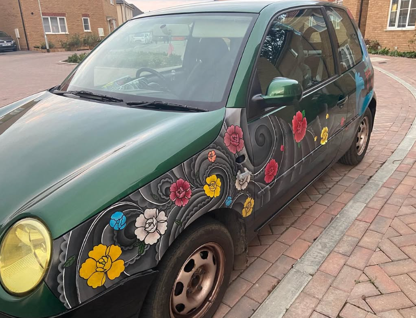 A photo of a green VW Lupo painted to look like it has Japanese tattoos.